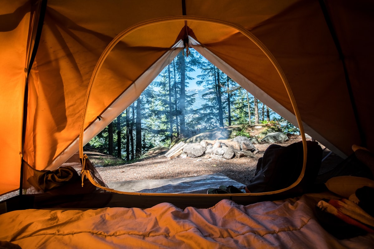 Camp tent illuminated under the stars next to lake